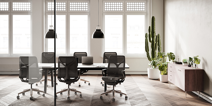 Büro mit Konferenztisch mit schwarzen Bürostühlen, großen Fenstern und einem Kaktus